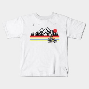 Dog riding a motorcycle with a mountain backdrop and sunset Kids T-Shirt